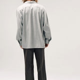 Back view of grey speckle church shirt on model wearing grey pants and boots, against a white background.