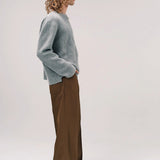 Side view of dove grey friends pullover sweater on model wearing brown pants and sneakers, against a white background.
