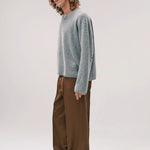 Alternate side view of dove grey friends pullover sweater on model wearing brown pants and sneakers, against a white background.
