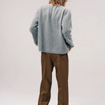 Back view of dove grey friends pullover sweater on model wearing brown pants and sneakers, against a white background.