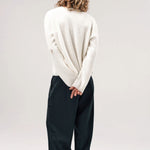 Back view of blanc friends pullover sweater on model wearing grey pants and boots, against a white background.