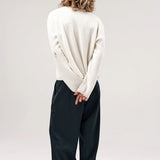Back view of blanc friends pullover sweater on model wearing grey pants and boots, against a white background.
