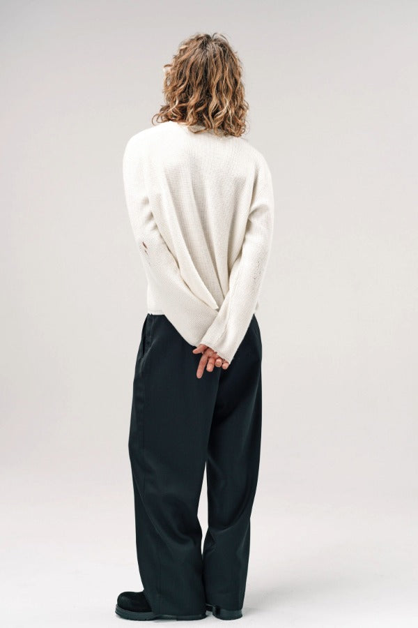 Back view of blanc friends pullover sweater on model wearing grey pants and boots, against a white background.