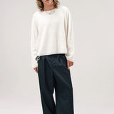 Alternate front view of blanc friends pullover sweater on model wearing grey pants and boots, against a white background.