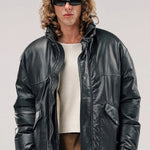 Front view of brown leather puffa jacket on model wearing white shirt and brown pants, against a white background.