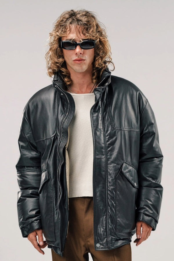 Front view of brown leather puffa jacket on model wearing white shirt and brown pants, against a white background.