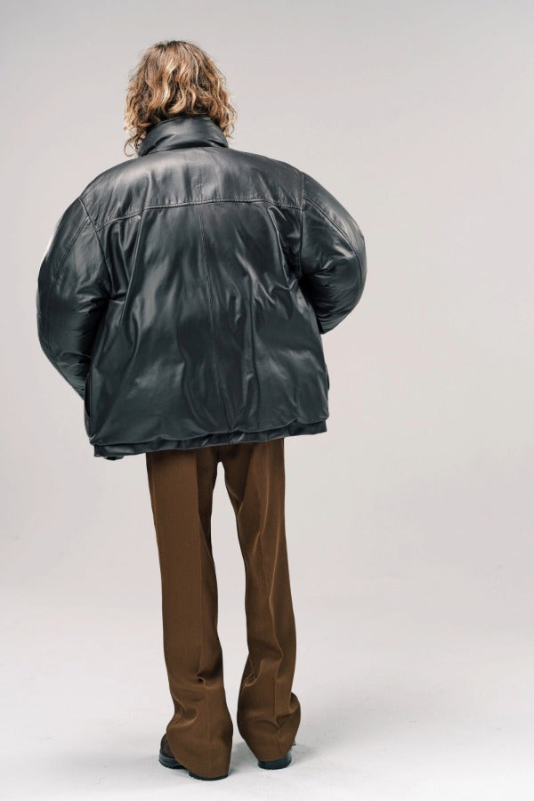 Back view of brown leather puffa jacket on model wearing brown pants and boots, against a white background.