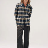 Alternate front view of olive check logan ombre ls shirt on model wearing white shirt, grey pants and boots, against a white background.