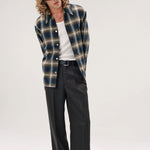 Alternate front view of olive check logan ombre s shirt on model wearing white shirt, grey pants and boots, against a white background.