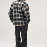 Back view of olive check logan ombre ls shirt on model wearing grey pants and boots, against a white background.