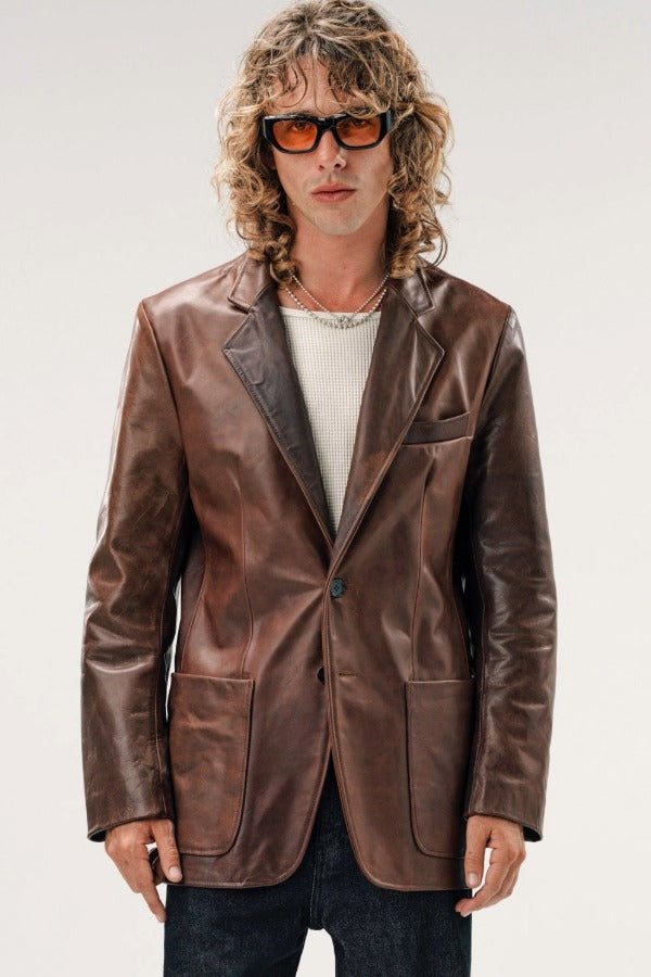 Front view of brown saico jacket on model wearing white shirt and jeans, against a white background.