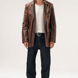 Alternate front view of brown saico jacket on model wearing white shirt, jeans and boots, against a white background.