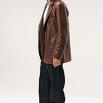 Side view of brown saico jacket on model wearing white shirt, jeans and boots. against a white background.