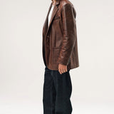 Side view of brown saico jacket on model wearing white shirt, jeans and boots. against a white background.