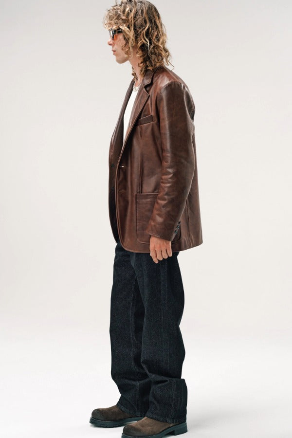Side view of brown saico jacket on model wearing white shirt, jeans and boots. against a white background.