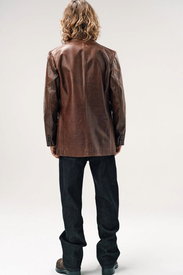 Back view of brown saico jacket on model wearing jeans and boots, against a white background.