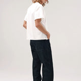 Side view of vintage white slappy pocket tee on model wearing jeans and boots, against a white background.
