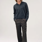 Alternate front view of black vexed v-neck sweater on model wearing grey pants and boots, against a white background.