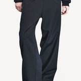 Front closeup view of titan midnight enes pants on model wearing navy jacket and boots, against a white background.