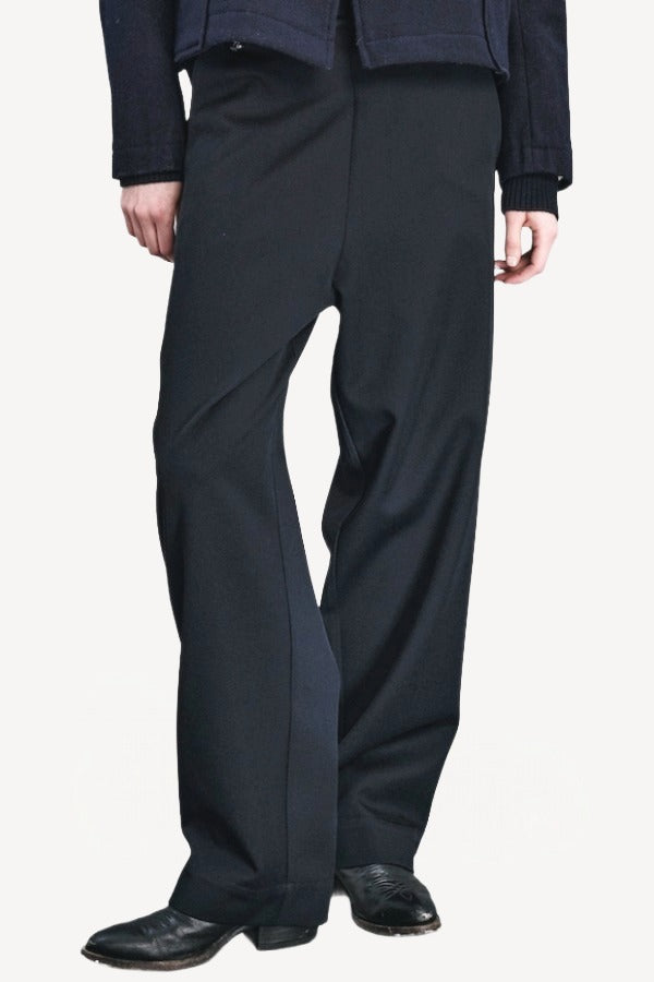 Front closeup view of titan midnight enes pants on model wearing navy jacket and boots, against a white background.