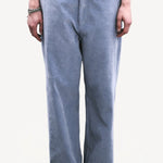 Front closeup view of blue ice esra marine pants on model wearing white top and boots, against a white background.