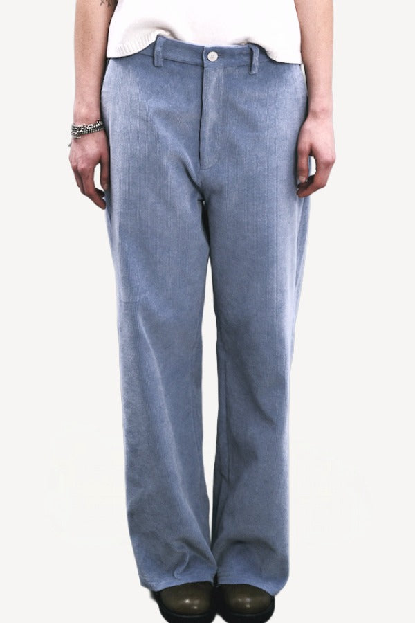 Front closeup view of blue ice esra marine pants on model wearing white top and boots, against a white background.