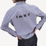 Back view of blue white stripe imny shirt on model wearing dark jeans, against a white background.