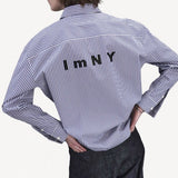 Back view of blue white stripe imny shirt on model wearing dark jeans, against a white background.