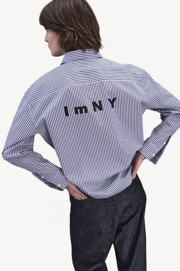 Back view of blue white stripe imny shirt on model wearing dark jeans, against a white background.