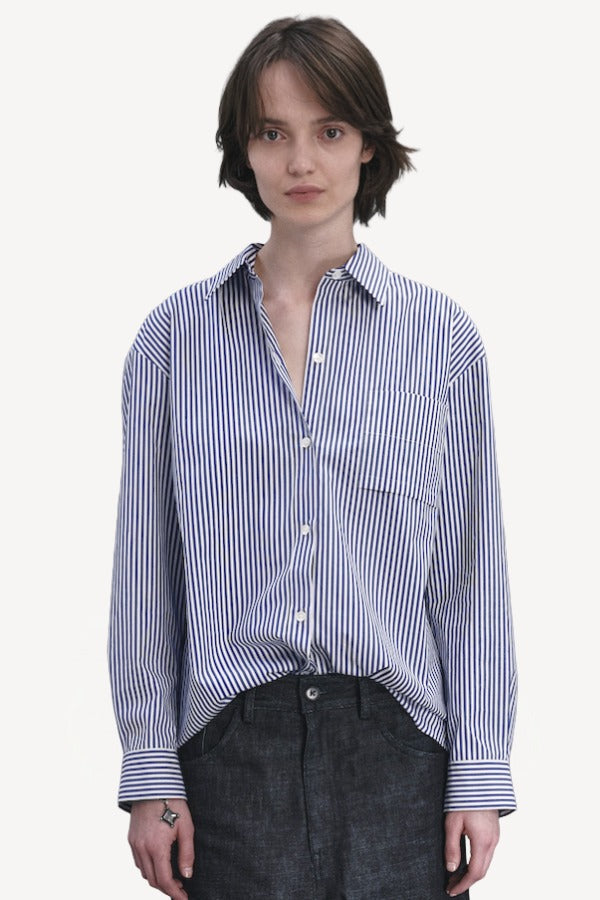 Front view of blue white stripe imny shirt on model wearing dark jeans, against a white background.