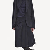 Front view of titan midnight kilt skirt on model wearing a black blazer and navy top with boots, against a white background.