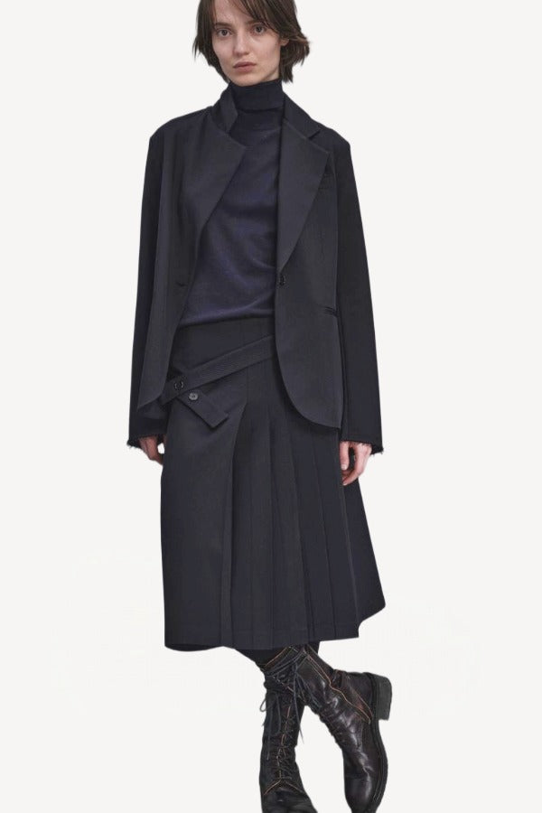 Front view of titan midnight kilt skirt on model wearing a black blazer and navy top with boots, against a white background.