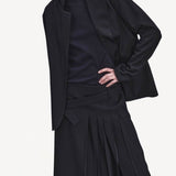 Alternate front view of titan midnight kilt skirt on model wearing black blazer, navy top and boots, against a white background.