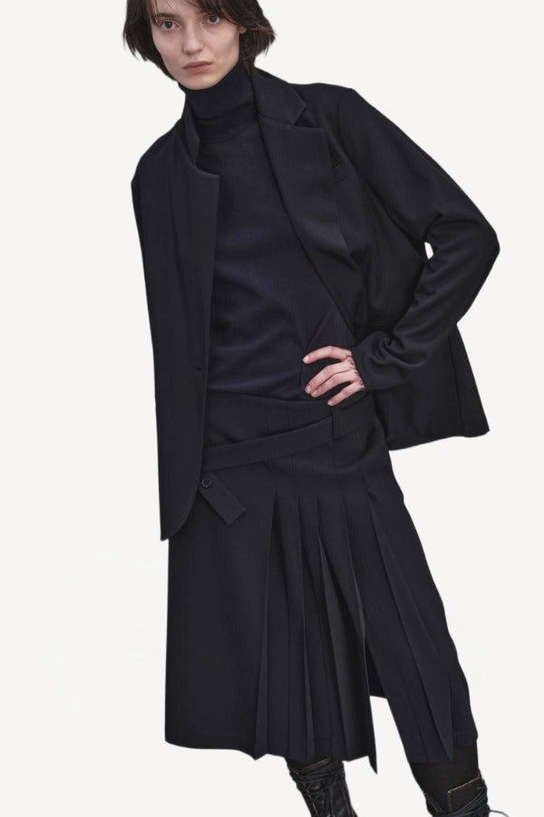 Alternate front view of titan midnight kilt skirt on model wearing black blazer, navy top and boots, against a white background.