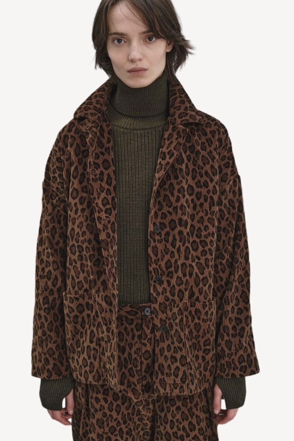 Alternate front view of leopard work jacket on model wearing green sweater and leopard pants, against a white background.