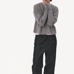 Front view of denim M pants on model wearing grey sweater and boots, against a white background.