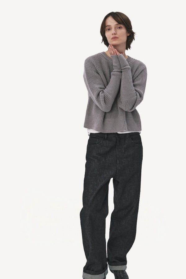 Front view of denim M pants on model wearing grey sweater and boots, against a white background.