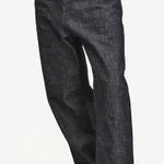 Front closeup view of denim M Pants on model wearing stripe shirt and boots, against a white background.