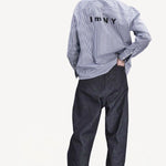 Back view of denim M Pants on model wearing stripe shirt and boots, against a white background
