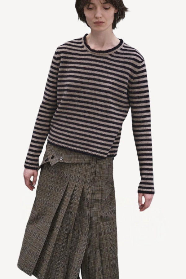 Front view of navy/oat sibs stripe sweater on model wearing plaid kilt, against a whiter background.