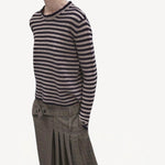Side view f navy/oat sibs stripe sweater on model wearing plaid kilt, against a white background.