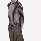 Side view f navy/oat sibs stripe sweater on model wearing plaid kilt, against a white background.