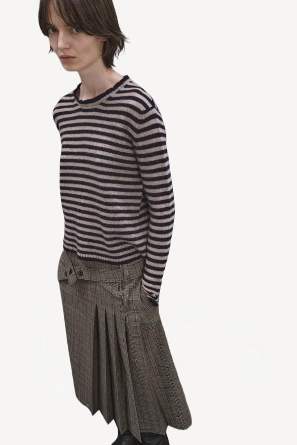Side view f navy/oat sibs stripe sweater on model wearing plaid kilt, against a white background.