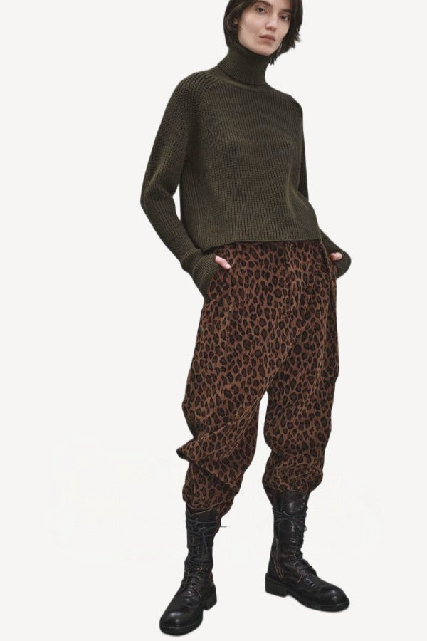 Front view of leopard yayla25 pants on model wearing green sweater and boots, against a white background.