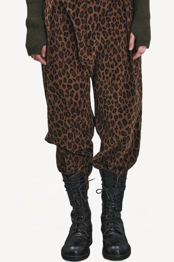 Front closeup view of leopard yayla25 pants on model wearing green sweater and boots, against a white background.