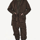 Front view of leopard yayla25 pants on model wearing green sweater, leopard jacket and boots, against a white background.