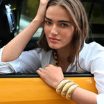 Front view of 18K YG Domed Cuff on brown-haired model wearing a white collared shirt, while posing out of taxi window.