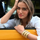 Front view of 18K YG Domed Cuff on brown-haired model wearing a white collared shirt, while posing out of taxi window.