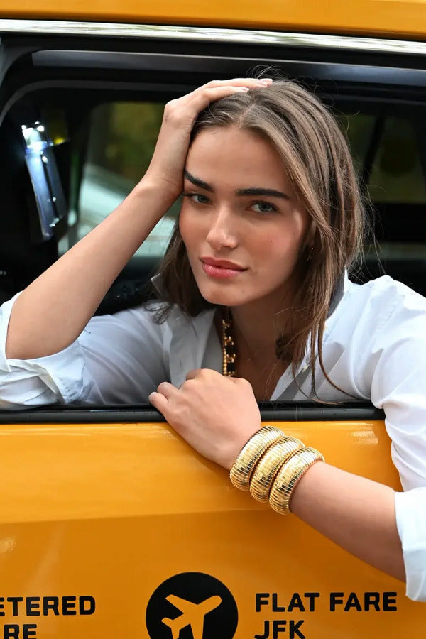 Front view of 18K YG Domed Cuff on brown-haired model wearing a white collared shirt, while posing out of taxi window.