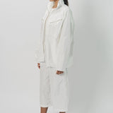 Side view of snow buck ls shirt on model wearing white shirt and pants, against a white background.